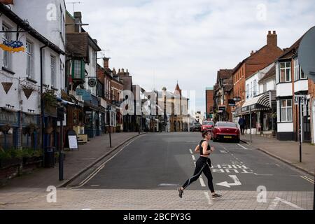 Una donna che corre in una Stratford-upon-Avon quasi deserta nel Warwickshire, mentre il Regno Unito continua a bloccarsi per contribuire a frenare la diffusione del coronavirus. Foto Stock