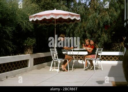 Una famiglia seduta su un tavolo sulla terrazza di una villa vacanze a St Maxime, nel sud della Francia, 1973 Foto Stock