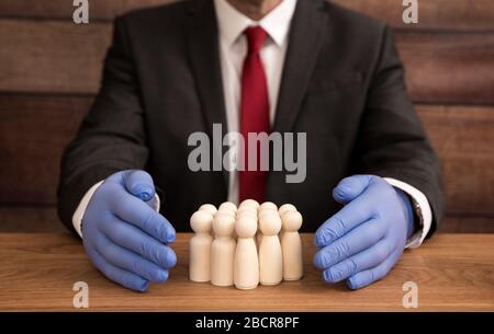 Un concetto di business e salute di un uomo d'affari che indossa un paio di guanti blu e chirurgici e protegge i suoi lavoratori, la forza lavoro e i dipendenti da una schermatura Foto Stock