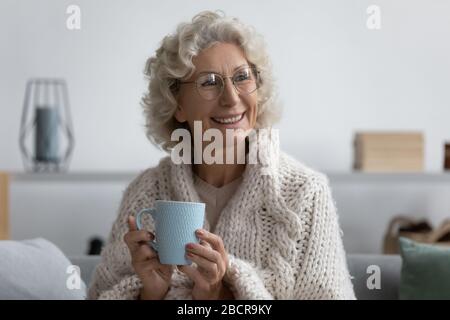 Felice donna di mezza età rilassata che si riscalda con una bevanda calda. Foto Stock