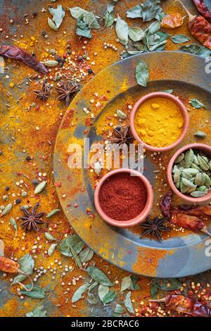 Spezie aromatiche su e intorno un piatto di peltro su sfondo ardesia Foto Stock