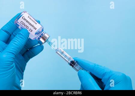 Mano del medico che indossa la siringa di contenimento e il vaccino COVID-19. Concetto di focolaio di Covid-19. Foto Stock