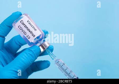 Mano del medico che indossa la siringa di contenimento e il vaccino COVID-19. Concetto di focolaio di Covid-19. Foto Stock