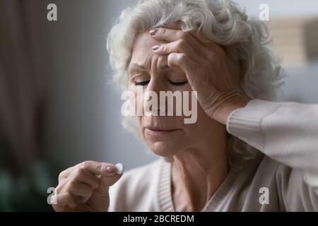 Nonna preoccupante di mezza età che prende le pillole painkiller. Foto Stock