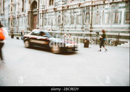 Sfocatura disfocusa vista della polizia Carabinieri auto italiana alla guida in piazza con silhouette di persone irriconoscibili durante la pandemia Coronavirus COVID-19 Foto Stock