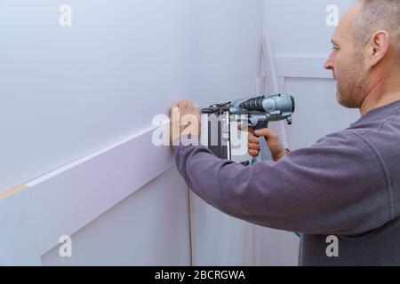 falegname mediante installazione a pistola di modanature sulla parete del frammento di stampaggio, Foto Stock