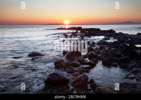 Tramonto sulla baia Messiniana in Grecia vista dalla spiaggia rocciosa di Agios Dimitrios Foto Stock