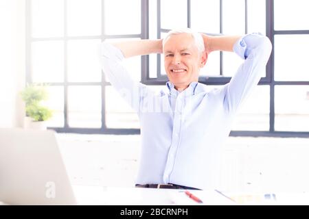 Scatto di un uomo sorridente soddisfatto che riposa sulla sedia durante il lavoro sul laptop a casa. Ufficio domestico. Foto Stock