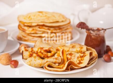 pancake russi fatti in casa, sottili e gustosi sul piatto con salsa di crema al cioccolato Foto Stock