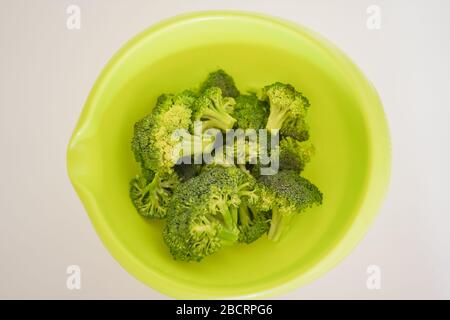 Espresso dall'alto in una ciotola verde brillante e vibrante riempita con steli di broccoli maturi pronti per una preparazione del pasto deliziosa e sana Foto Stock