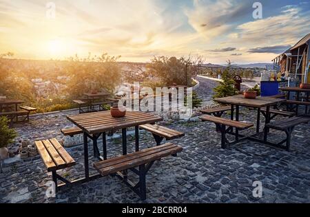 Ristorante con tavoli al punto di vista sulla collina di Goreme al bel tramonto, Cappadocia, Turchia Foto Stock