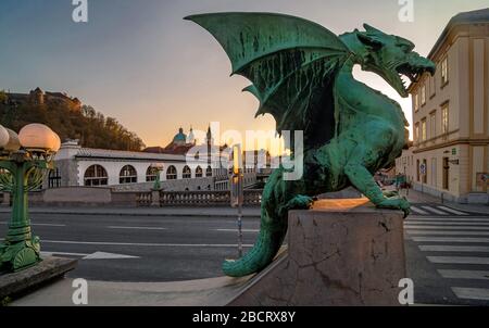 Statua del drago sul ponte del drago e la cattedrale di San Nicola sullo sfondo al tramonto, Lubiana, Slovenia Foto Stock