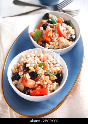 Insalata di farro con tonno in scatola in olio d'oliva, pomodori, olive nere e menta Foto Stock