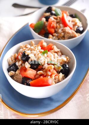 Insalata di farro con tonno in scatola in olio d'oliva, pomodori, olive nere e menta Foto Stock