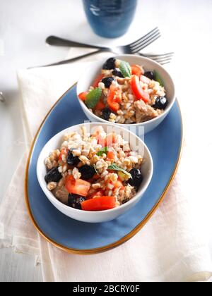 Insalata di farro con tonno in scatola in olio d'oliva, pomodori, olive nere e menta Foto Stock