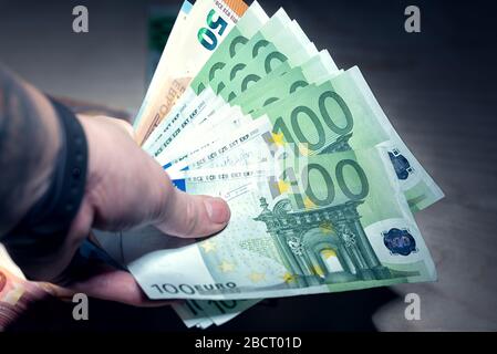 Mucchio di banconote in euro verdi e contornate in mano Foto Stock