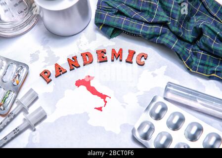 Pandemia di parola piegata dalle lettere rosse sulla mappa del mondo con l'Italia rossa. Equiment medico, maschera e pillole intorno. Concetto di allarme per la protezione da pandemia virale Foto Stock