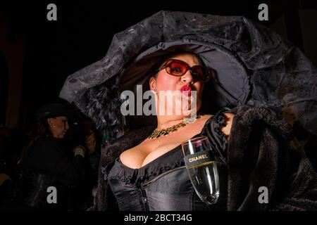 Donna, vestita con abiti lutto e sorridente, che si sfilava per le strade durante la processione funeraria sepoltura della Sardina Foto Stock