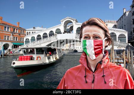 Donna con maschera facciale di protezione con bandiera italiana contro il coronavirus di fronte al ponte di Rialto, Venezia, Italia Foto Stock