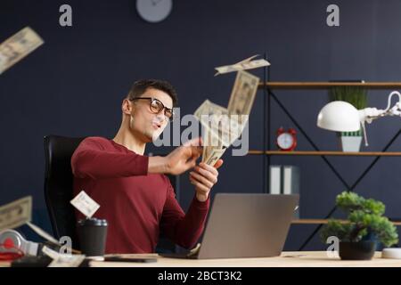 Sono ricco. Ritratto di un giovane freelancer o uomo d'affari in un hom Foto Stock