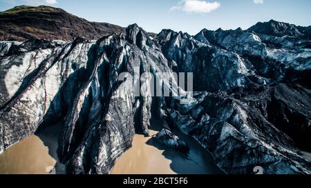 Vista aerea ravvicinata del ghiacciaio Solheimajokull e della laguna glaciale di fronte ad esso sparata in estate con un drone. Foto Stock