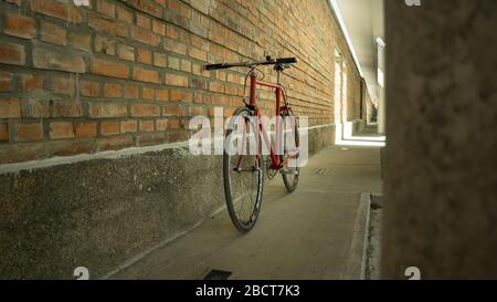 Bici a ingranaggi fissi in stile retrò rosso a singlespeed isolata su una parete in mattoni Foto Stock