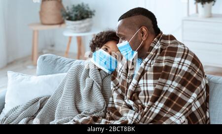 Pericolo di diffusione del virus. Famiglia Afro-americana che rimane a casa, indossando maschere protettive, spazio vuoto. Panorama Foto Stock