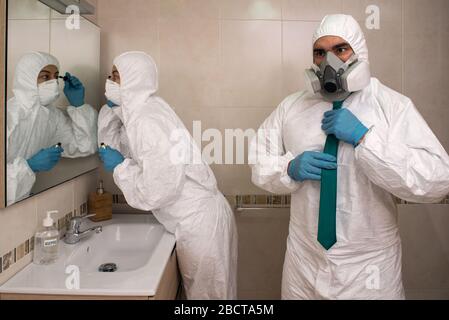 Coppia di uomo e donna che si preparano ad uscire in bagno vestito con tute protection NBC durante la crisi del coronavirus 19. Foto Stock