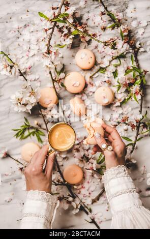 Le mani delle donne tengono biscotti macaron e caffè fresco Foto Stock