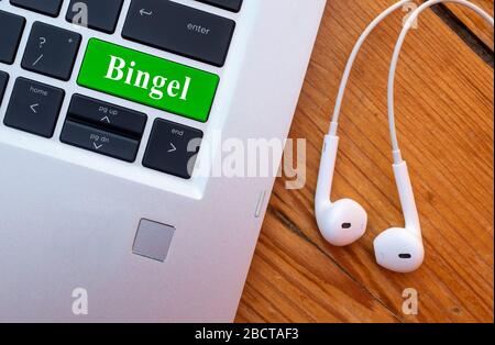 Laptop con cuffia e parola Bingel sulla tastiera. Bingel è una piattaforma belga per la scuola domestica. Foto Stock