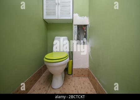 WC nel bagno. Servizi igienici con pareti dipinte di verde per lavori di ristrutturazione Foto Stock