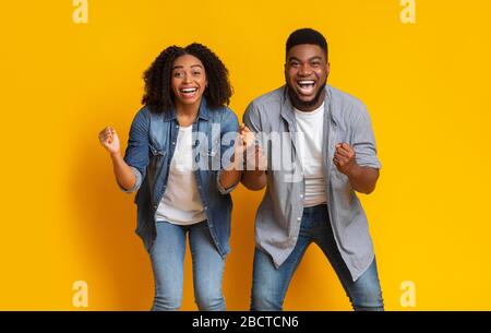Coppia nera euforica rallegrandosi con le fiaccate e urlando con l'eccitazione Foto Stock