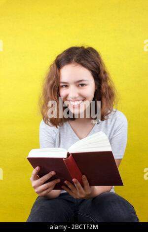 Curly bella ragazza legge libro divertente e ride Foto Stock