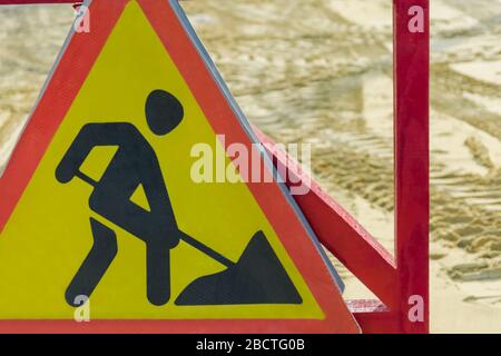 cartello stradale nel pomeriggio sullo sfondo dei cingoli del trattore Foto Stock