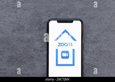 Smartphone con logo dell'app Zoom Inside House Working Remote From Home Quarantine o Lockdown Concept on Natural Stone background. Foto Stock