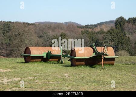 due campi rullo su un piccolo prato, foresta e colline sullo sfondo, cielo blu Foto Stock