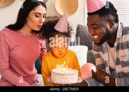 Famiglia che soffia fuori le candele su una torta Foto Stock