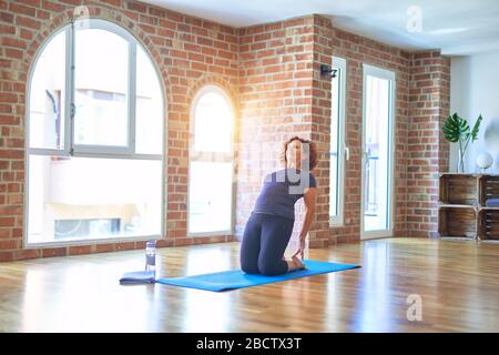 Età media bella spsportwoman sorridente felice su stuoia. Praticare lo yoga facendo una posa in cammello in palestra Foto Stock