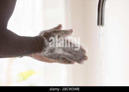 Giovane afro americano uomo lavando le mani con sapone antibatterico bolla. Foto Stock