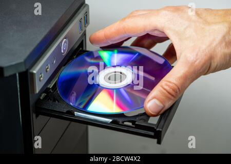 Mano che inserisce il DVD in un computer. Primo piano. Foto Stock