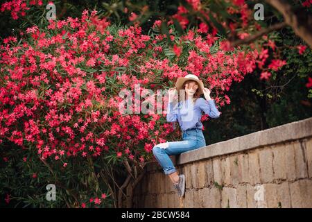 Una giovane donna su uno sfondo di fiori viola. Una ragazza sorride accanto ad un albero fiorente con fiori viola, faccia da vicino Foto Stock