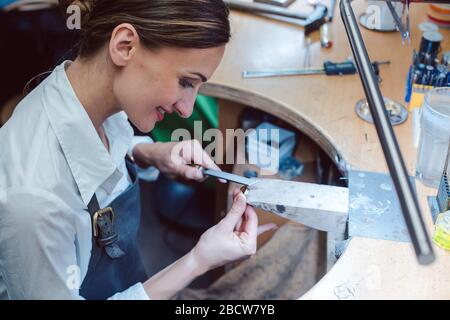 Gioielliere che lavora con gli attrezzi su un pezzo di gioielleria Foto Stock