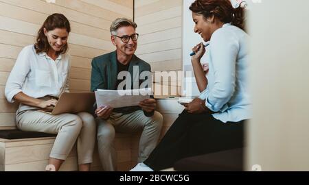 Professionisti aziendali multietnici che progettano nuove idee di marketing in un incontro. Team di lavoro creativo che discute nuove strategie in ufficio. Foto Stock