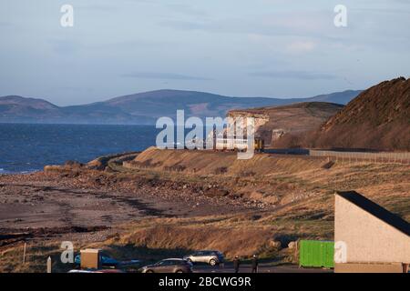 Treno ferroviario nord di classe 156 sprinter ad Harrington sulla linea ferroviaria panoramica della costa Cumbria che corre lungo il mare irlandese con Solway Firth Beyond Foto Stock