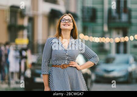 Viaggio europeo, città vecchia, vacanza estiva. Ritratto di giovane donna. Giovane bella donna in un abito blu in un vicolo della città, con luci LED in Foto Stock