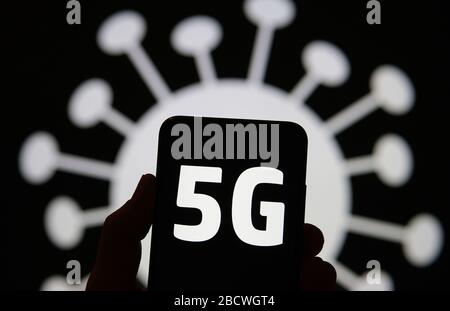 Radiazione 5G a forma di COVID-19. Le lettere 5G sulla silhouette dello smartphone tengono in mano e l'immagine del coronavirus sullo sfondo. Foto vera, non un m Foto Stock