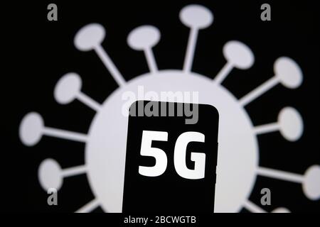 Radiazione 5G a forma di COVID-19. Le lettere 5G sulla silhouette dello smartphone tengono in mano e l'immagine del coronavirus sullo sfondo. Foto vera, non un m Foto Stock