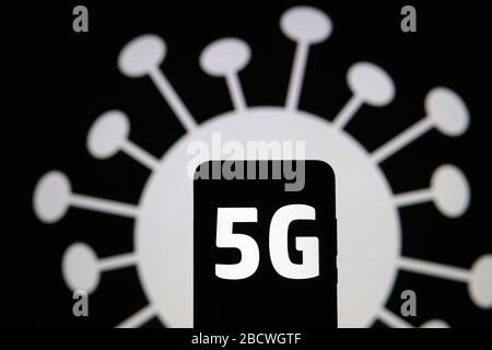 Radiazione 5G a forma di COVID-19. Le lettere 5G sulla silhouette dello smartphone tengono in mano e l'immagine del coronavirus sullo sfondo. Foto vera, non un m Foto Stock