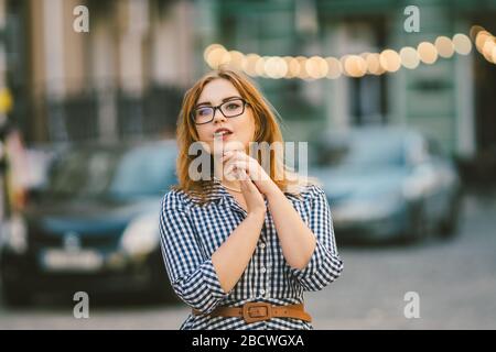 Viaggio europeo, città vecchia, vacanza estiva. Ritratto di giovane donna. Giovane bella donna in un abito blu in un vicolo della città, con luci LED in Foto Stock