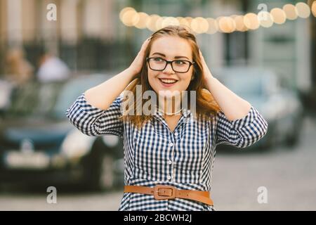 Viaggio europeo, città vecchia, vacanza estiva. Ritratto di giovane donna. Giovane bella donna in un abito blu in un vicolo della città, con luci LED in Foto Stock